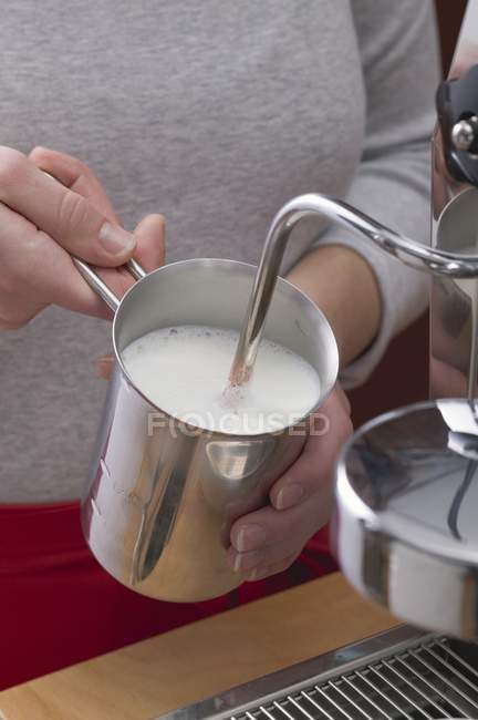 Woman frothing milk — Stock Photo