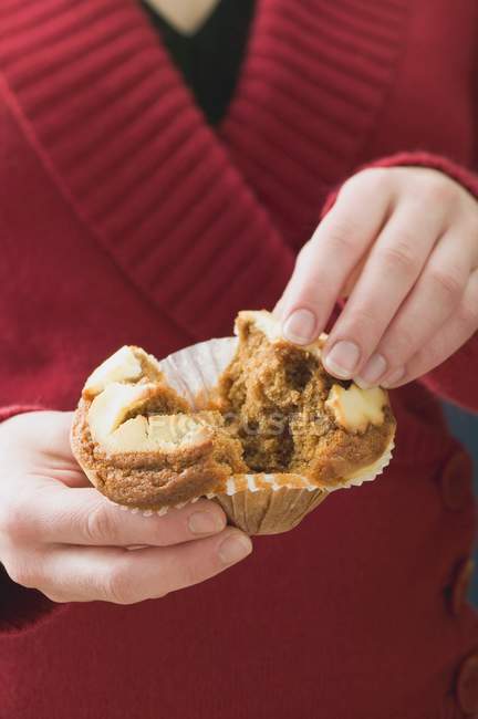 Woman halving muffin in paper case — Stock Photo