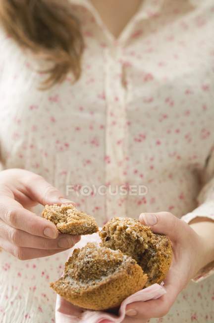 Femme tenant un muffin coupé en deux — Photo de stock