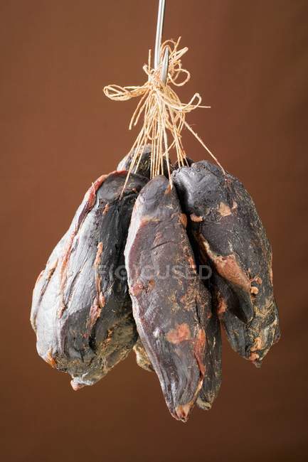 Closeup view of smoked venison ham hanging on a hook — Stock Photo