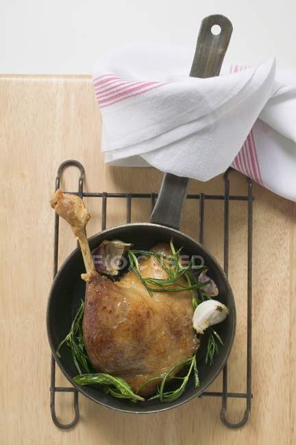 Top view of fried goose leg with rosemary in frying pan — Stock Photo