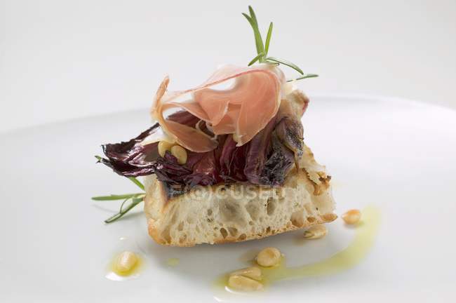 Pane piatto condito con radicchio, prosciutto di Parma e pinoli su piatto bianco — Foto stock