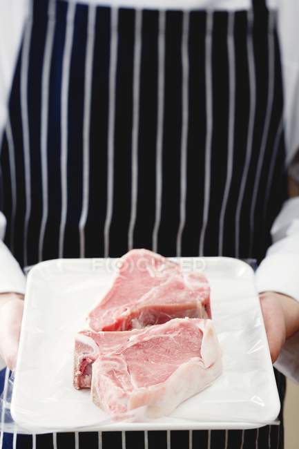 Chef holding pork chops — Stock Photo