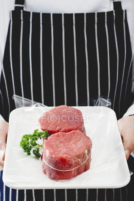 Homem segurando fatias de filé de carne bovina — Fotografia de Stock
