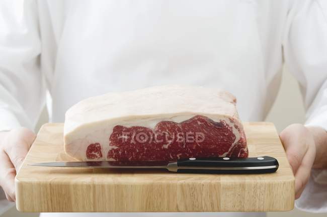 Chef tenant un morceau d'aloyau de bœuf cru — Photo de stock