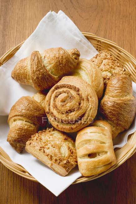Closeup top view of assorted pastries in small basket on wood surface — Stock Photo