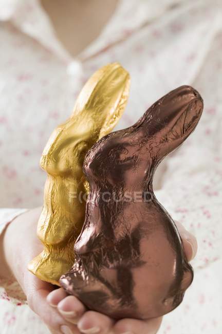 Mãos femininas segurando coelhos de Páscoa — Fotografia de Stock