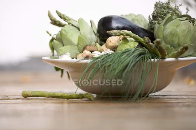 Bol de légumes : artichauts, aubergines, ciboulette, etc. sur plaque blanche — Photo de stock
