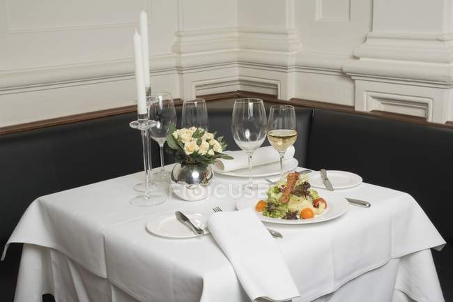 Nahaufnahme von Salat und Weißwein auf gedecktem Tisch im Restaurant — Stockfoto