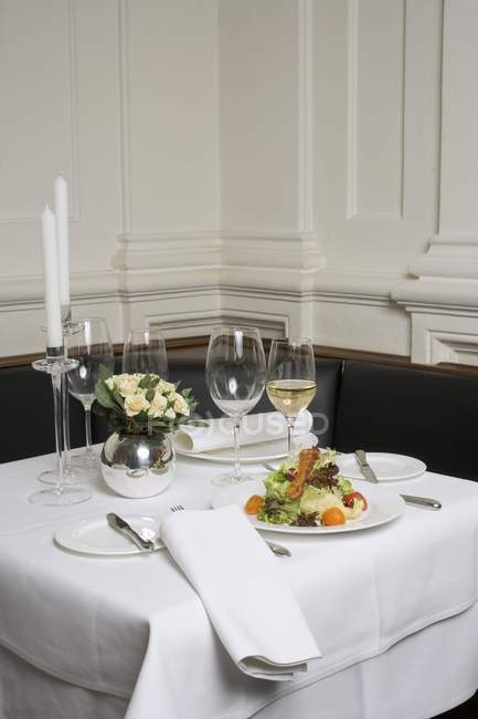Салат и белое вино на накрытом столе в ресторане — стоковое фото