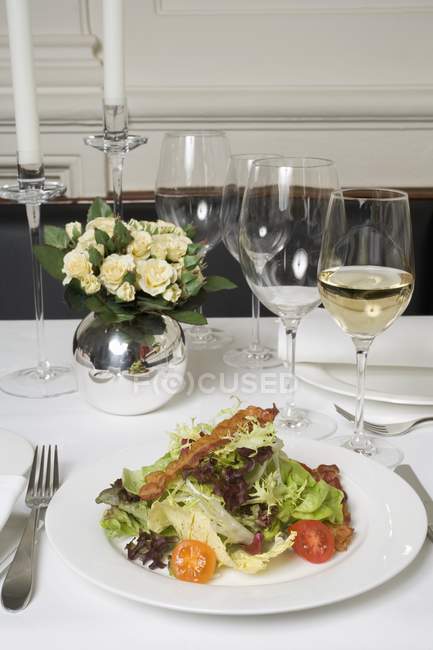 Salad with bacon and glasses of wine — Stock Photo