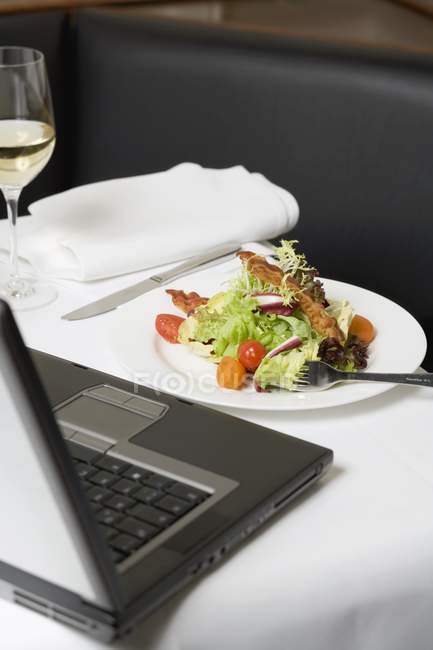 Vista da vicino dell'insalata con pancetta davanti al computer portatile — Foto stock