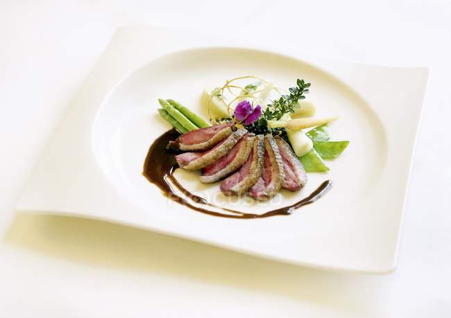 Cold-smoked duck breast with vegetables on white plate over white surface — Stock Photo