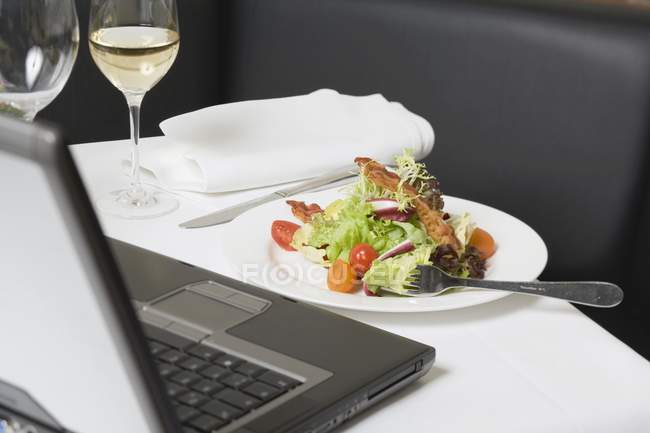 Vista close-up de salada com bacon na frente do laptop — Fotografia de Stock