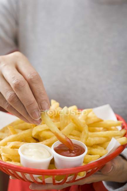 Person dipping fried chip in ketchup — Stock Photo