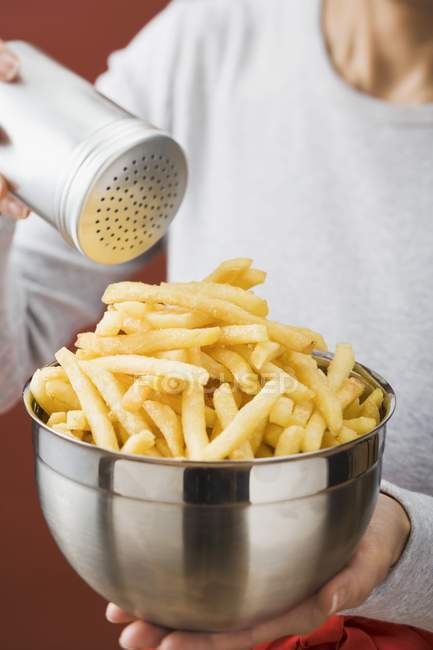 Woman putting salt on fried chips — Stock Photo