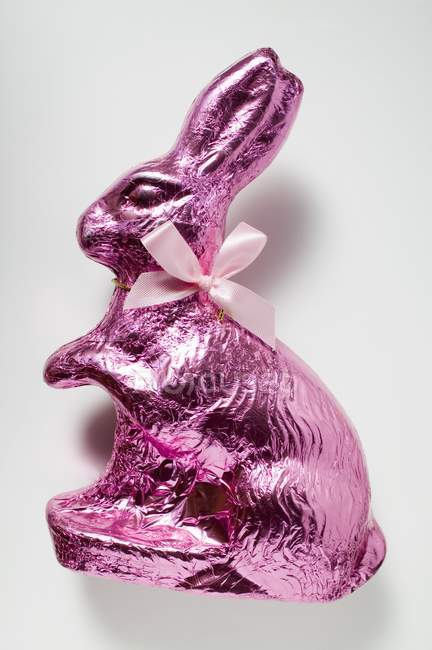 Conejito de chocolate en papel de aluminio rosa - foto de stock