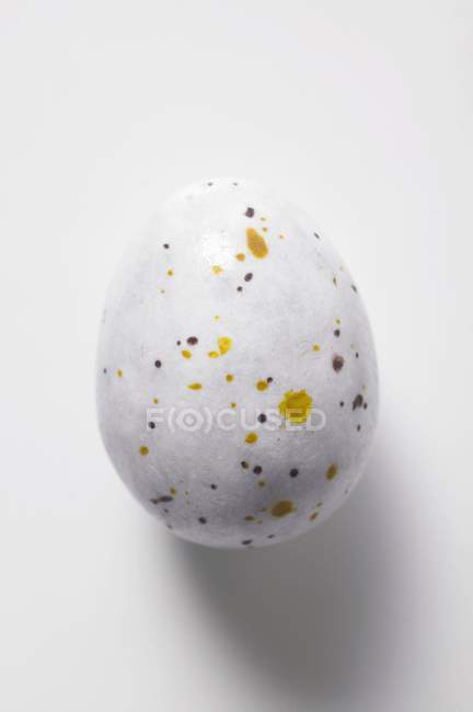 Vista de primer plano del huevo de chocolate moteado en la superficie blanca - foto de stock