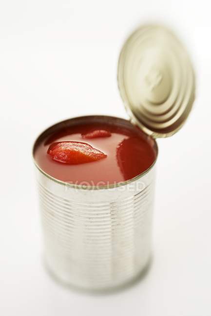 Estanho aberto de tomates sobre fundo branco — Fotografia de Stock