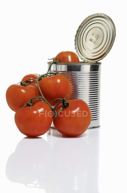 Estaño de tomate abierto con tomates frescos - foto de stock