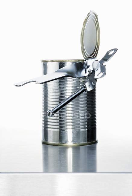 Closeup view of a tin can and a tin opener — Stock Photo