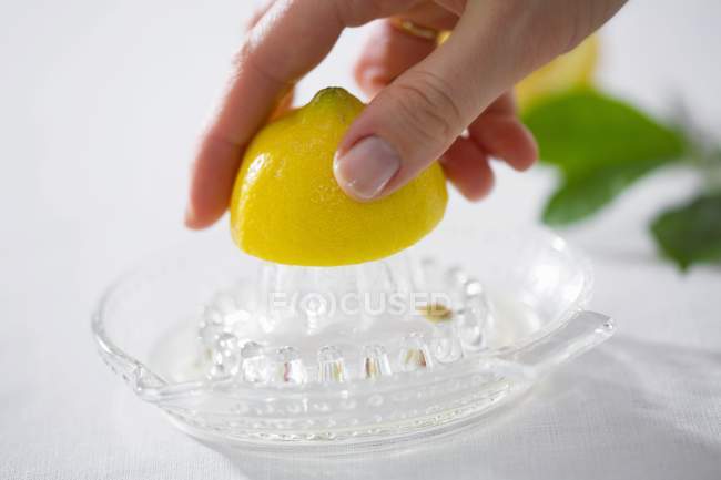 Mano femminile spremitura limone — Foto stock