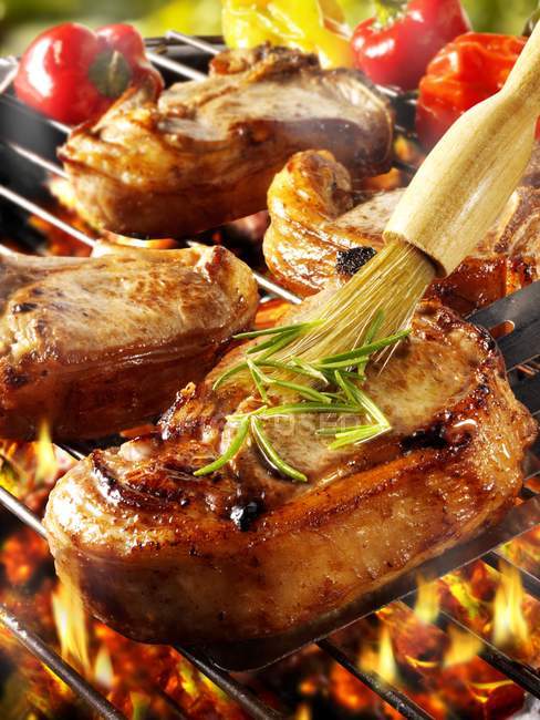 Brosser la côtelette de porc sur le porte-barbecue — Photo de stock