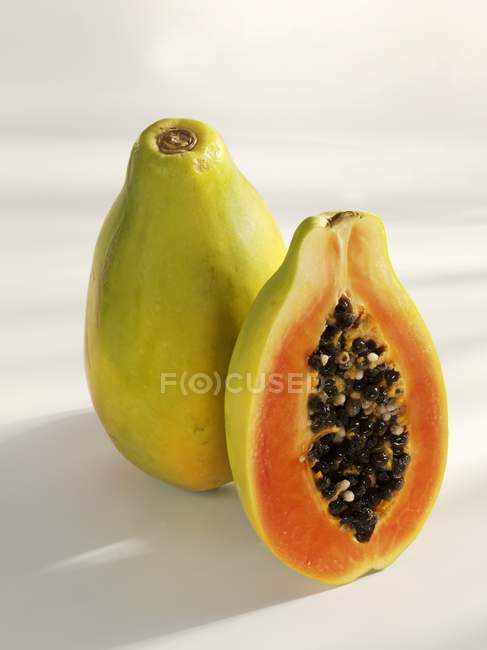 Papaya fresca entera y media - foto de stock