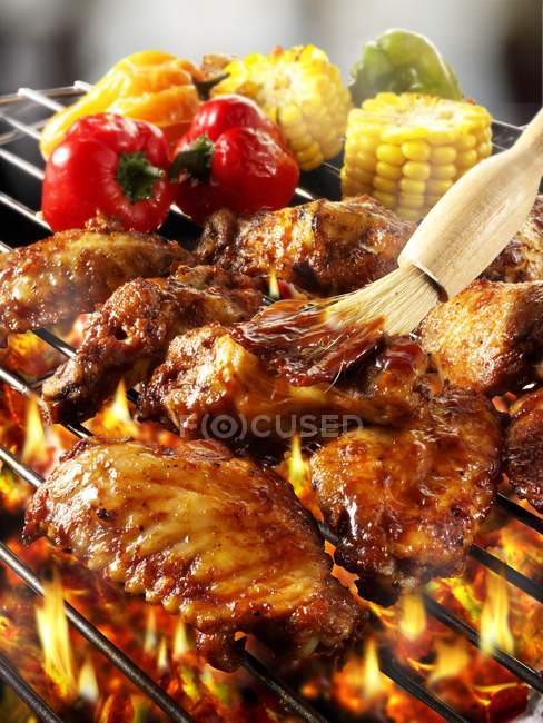 Vue rapprochée du brossage des ailes de poulet sur grille à barbecue avec marinade — Photo de stock