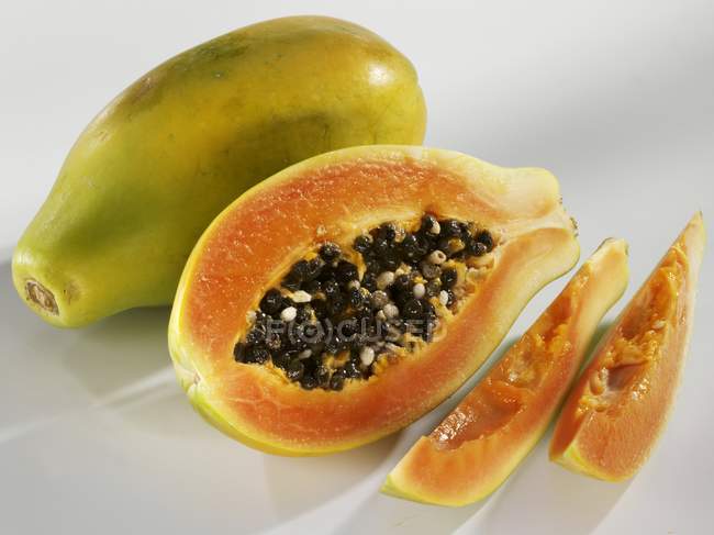 Papaya fresca entera y cortada en rodajas - foto de stock