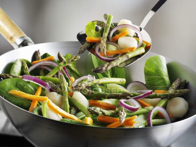 Verduras en carne wok negro sobre fondo gris - foto de stock