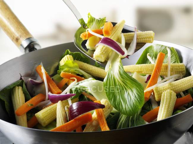 Verdure e pannocchie di mais bambino nel wok con sfondo sfocato — Foto stock