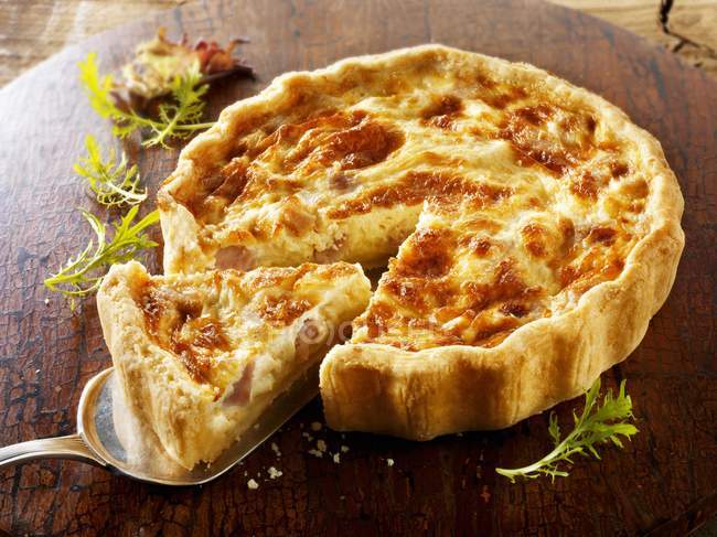 Close up view of cut Quiche Lorraine with slice on server — стоковое фото