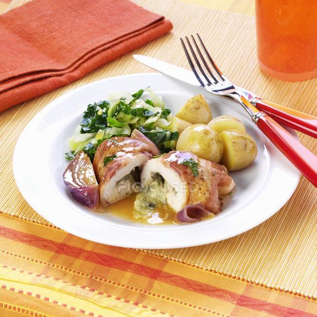 Involtini di pollo ripieni avvolti nella pancetta su piatto bianco con forchetta e coltello — Foto stock