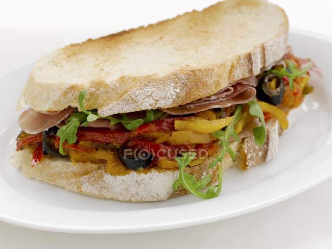 Pepper, olive and Parma ham sandwich  on white plate — Stock Photo