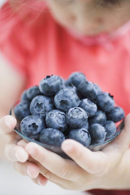 Child holding glass dish of blueberries — Stock Photo