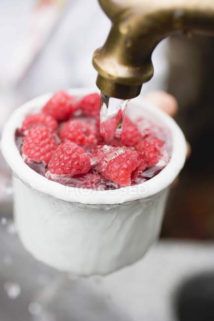 Human hands washing raspberries — Stock Photo