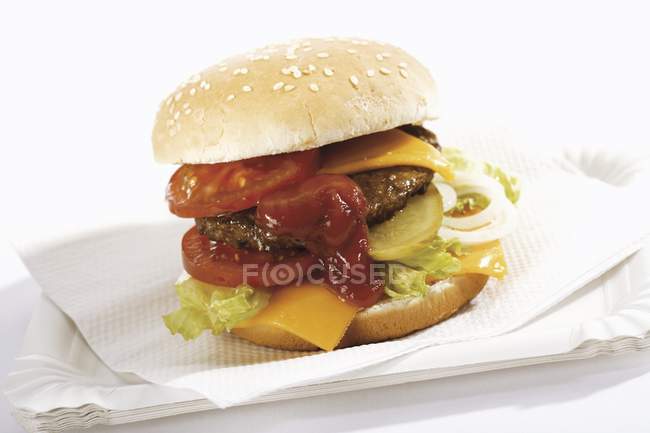 Vista de cerca de una hamburguesa sobre papel blanco y platos de papel - foto de stock