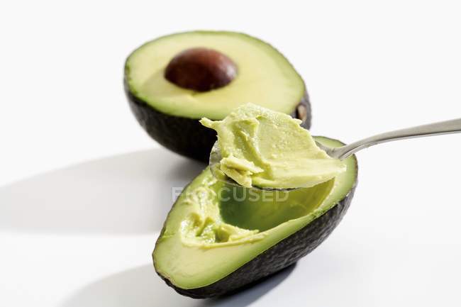 Hollowing out avocado with spoon — Stock Photo