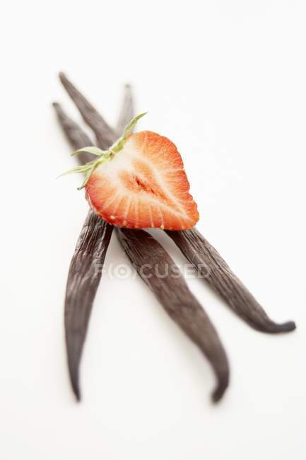 Half strawberry on three vanilla pods — Stock Photo