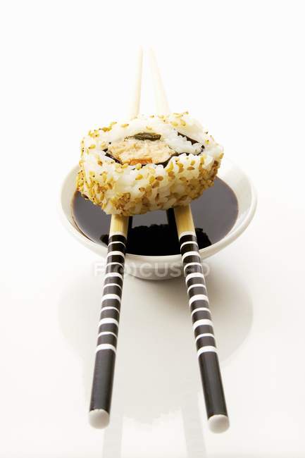 Ura maki sushi on chopsticks — Stock Photo
