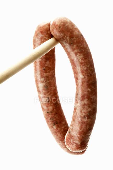 Sausages hanging on wooden spoon — Stock Photo