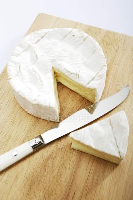 Camembert with piece on cutting board — Stock Photo
