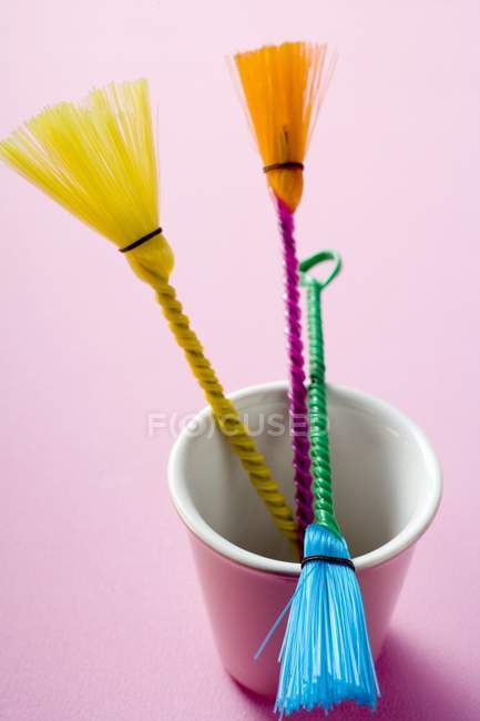 Closeup view of three colored pastry brushes in pink beaker — Stock Photo