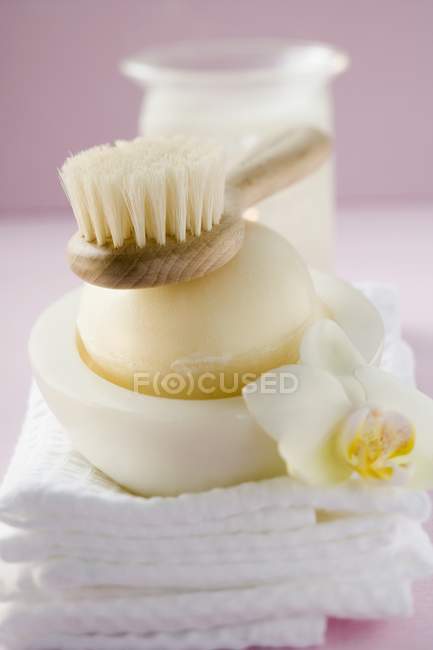 Vista de primer plano de jabón perfumado en jabonera en toallas, cepillo y parabrisas - foto de stock