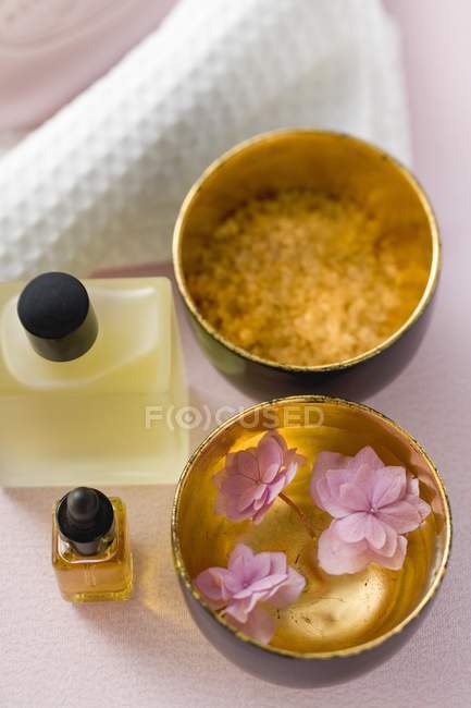Closeup elevated view of bath products, flowers in bowl of water and towel — Stock Photo