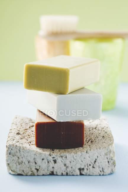 Trois barres de savon sur pierre ponce avec des phares et une brosse — Photo de stock