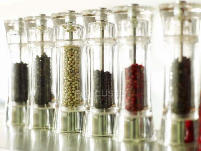 Vista close-up de vários tipos de pimenta em várias peppermills — Fotografia de Stock