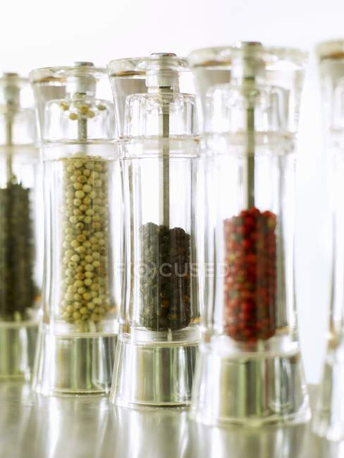 Closeup view of pepper mills with different types of pepper — Stock Photo
