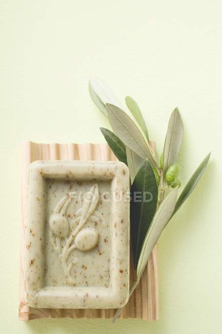 Olive soap and olive branch over green background — Stock Photo